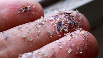 Foto close-up dari samping mikroplastik yang menempel di tangan manusia. Foto: Getty Images/iStockphoto/pcess609